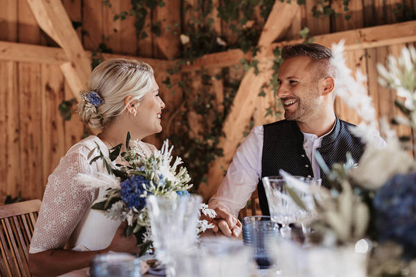 Lächelndes Brautpaar zu Tisch auf der Stadlbergalm